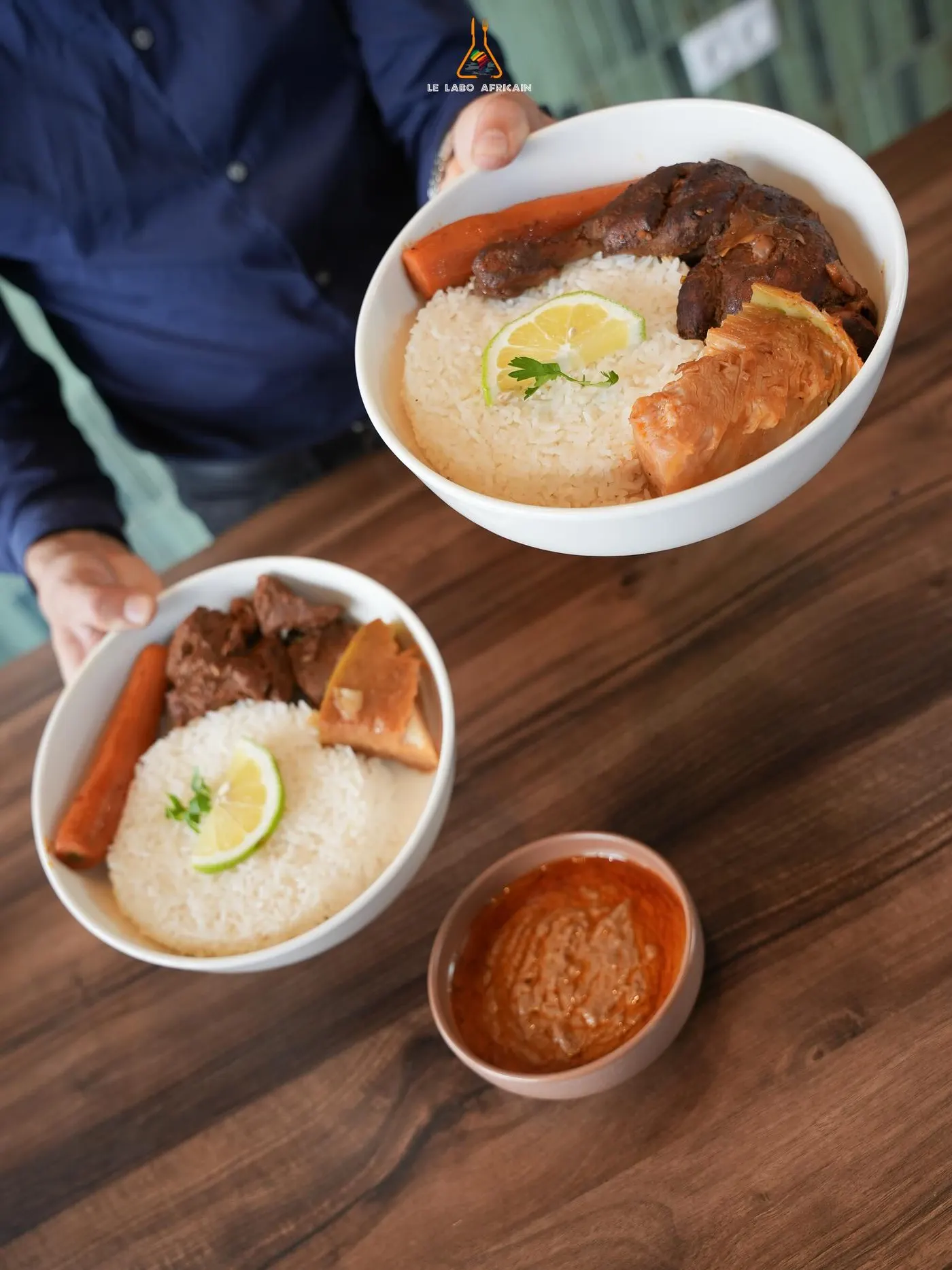 Two bowls of chicken yassa with rice handed over the counter