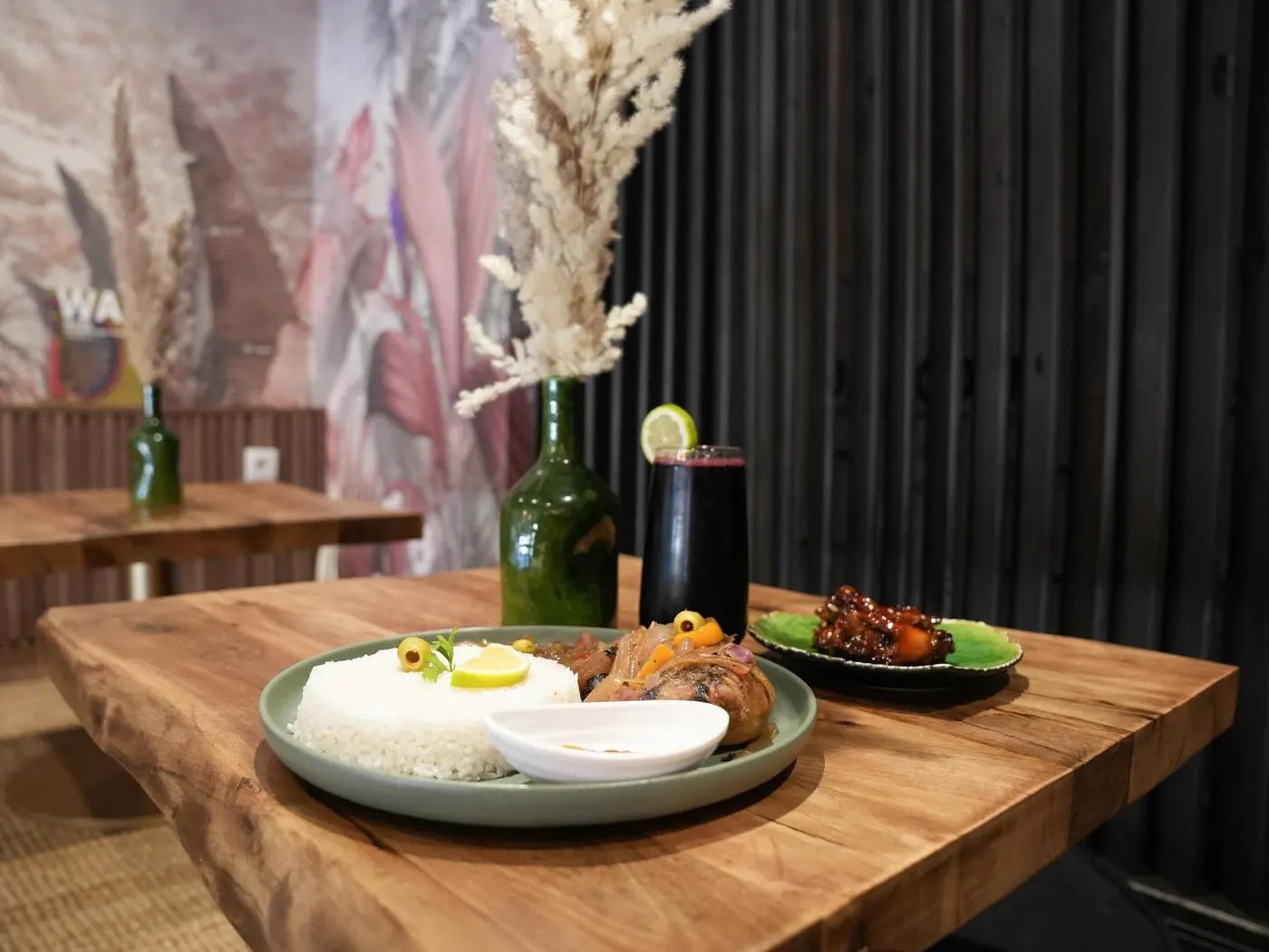 A set wooden table with dried flowers against the dark dining-room wall